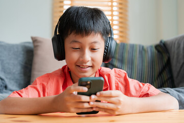 portrait. asian boy playing online game on smart phone with headphones .