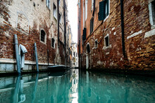 On A Gondola Boat In Venice Italy Between Brick Houses