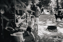 A Boy Chops Wood As His Father Watches