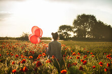 Girl Walking With Balloons Amidst Poppy Flowers