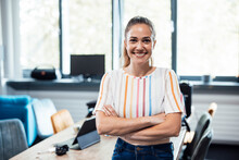 Happy Businesswoman With Arms Crossed Standing At Office