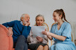© Westend61 - Smiling nurse assisting senior man and woman reading medical reports at home