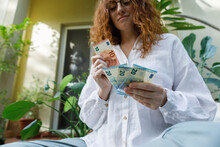 Woman Counting Paper Currency In Backyard