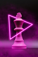 creative photo of the king of chess with led and smoke purple pink. vertical photo with subject clos