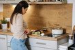 © Aleksandr - Back view of female cutting different vegetables for preparing vegan dish at her kitchen
