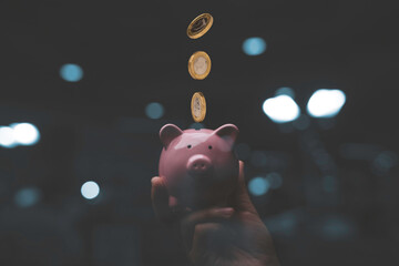 Wall Mural - Businessman holding pink piggy bank with dropping coins  , Money saving and deposit for investment to get profit and dividend concept.