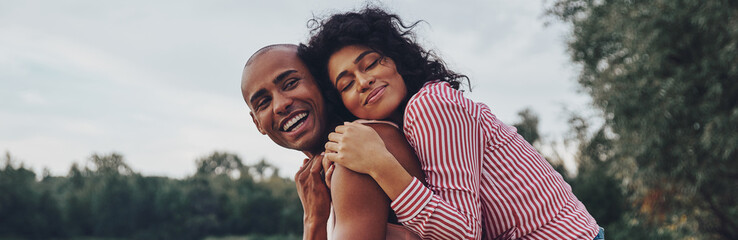 Poster - Happy young couple embracing and smiling while sitting outdoors