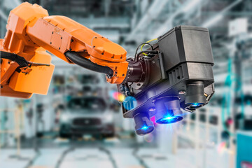 Industrial 3D laser scanner on robotic arm on background of car manufacturing factory. Automated robot arm assembly line manufacturing. Development and production of automotive technologies.