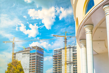 Wall Mural - Construction cranes and unfinished modern skyscrapers against the backdrop of a classic building. New architectural solutions to replace the old ones.