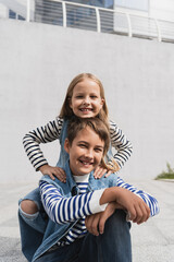 Poster - pleased girl in stylish clothes leaning on shoulders of happy well dressed boy near mall.