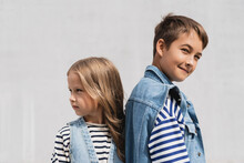 Well Dressed Boy And Girl In Denim Outfits Looking At Camera While Standing Outdoors.