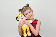Happy And Smiling Child Hugging Tiger Toy On White Background Caucasian Little Girl Kid Of 6 7 Years In Red Plaid Dress Looking At Camera