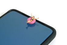 Miniature People Toy Figure Photography. Virtual Travel Concept, Girl Swimming With Rubber Tube Ring Above Smartphone, Isolated On White Background