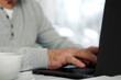© Marina Demidiuk - Closeup of senior man hands using laptop. Cropped side view of wrinkled caucasian older hands typing keyboard. Old people with technology. Unrecognizable retired male working from home sitting at desk