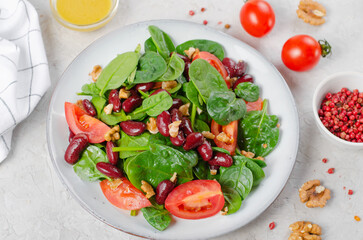 Wall Mural - Red Bean Salad On Bright Background, Fresh Salad with Spinach, Cherry Tomatoes, Walnuts, Beans and Mustard Dressing