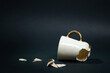 Broken tea cup isolated on black background. Cracked coffee mug and fragile ceramic pieces