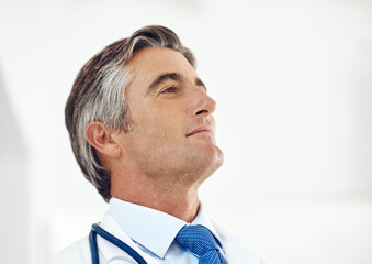 Poster - Proud of another job well done. a handsome mature male doctor looking thoughtful while standing in the hospital.