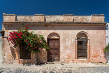 stone house with red flowers on stone wall in colonia del sacramento uruguay