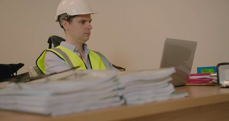 Wall Mural - Construction engineer man in the Hard Hat working sitting at table using laptop at work in workspace