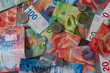 Many coins lie on the scattered banknotes. The Swiss franc is very strong and the Swiss economy is good.