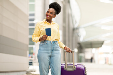 Wall Mural - Cheerful African American Female Tourist Holding Passport Posing Near Airport