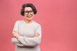 Senior happy aged business woman wearing glasses. Beautiful old woman, grandmother looking at camera and smiling. Isolated on pink background.