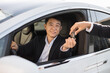 © sofiko14 - Portrait of pleased asian man in black suit receiving car keys from male dealership seller. Happy male in formal attire buying news luxury vehicle. Concept of successful business and consumerism.