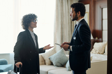 Aufkleber - Mature businesswoman with suitcase communicating with head manager of luxurious five star hotel while standing in front of him in room