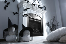 Beautiful Black Witch Hats On Pumpkins Near Fireplace Indoors. Halloween Celebration