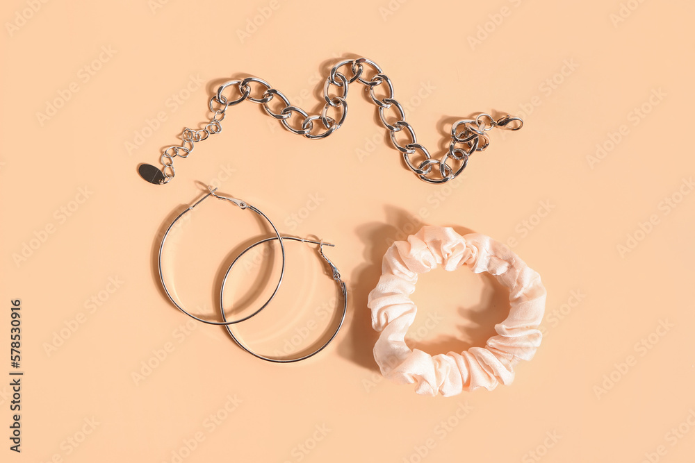 Silk scrunchy, earrings and bracelet on color background