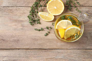 Canvas Print - Aromatic herbal tea with thyme and lemon on wooden table, flat lay. Space for text