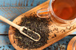 Board with cup of tasty hot tea and dry leaves on color wooden table, closeup