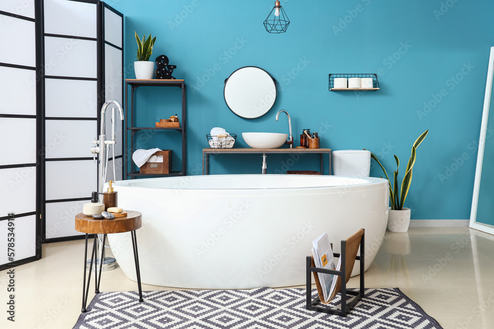 Interior of bathroom with sink, bathtub and shelving unit