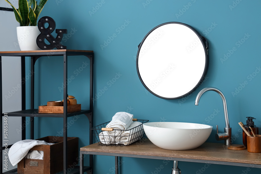 Interior of bathroom with white sink, mirror and shelving unit