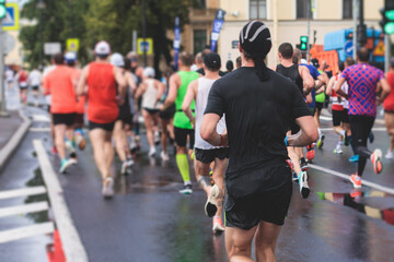 Wall Mural - Marathon runners crowd, participants start running the half-marathon in the city streets, crowd of joggers in motion, group athletes outdoor training competition in the rain