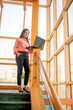 © Niks Ads - Indian corporate woman standing on office stair and using laptop.