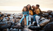 © Anela R/peopleimages.com - Travel, beach and family sitting on rocks while on summer vacation, adventure or weekend trip. Happy, smile and portrait of mother bonding with her children and husband by the ocean while on holiday.