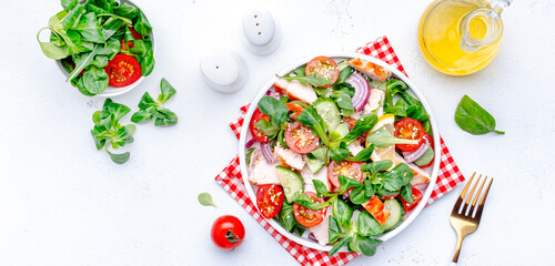 Wall Mural - Fresh salad with grilled chicken slice with red tomato, cucumber, red onion, lamb lettuce and sesame seeds on white table background, top view