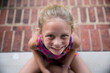 © Cavan Images - Closeup of Happy, Tan, Blonde, Young Girl Sitting on Brick Patio