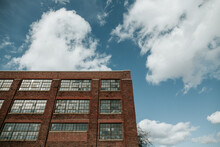 Brick Building Against A Blue Sky With White Clouds