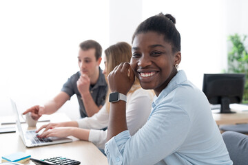 Portrait of african american clerk smiling at camera while coworkers work together in the office