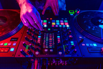 Close up of DJ hands on dj console mixer during concert in the club