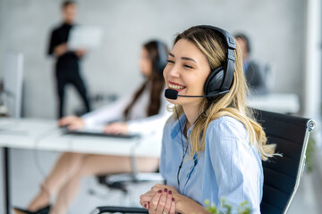 Wall Mural - Adorable blond haired woman with headset chatting with customer at call center.