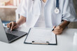 © NINENII - Doctor working on laptop computer and tablet and medical stethoscope on clipboard on desk, electronics medical record system EMRs concept.