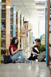 © DragonImages - Group of students sitting on library floor