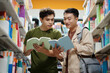 © DragonImages - Cheerful college students discussing new books in library
