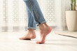 © New Africa - Barefoot woman walking on white parquet at home, closeup. Heated floor