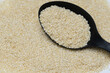 Czarna plastikowa łyżka kuchenna pełna ziarenek łuskanego białego sezamu