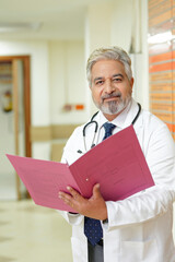 Wall Mural - Indian senior doctor watching medical report at hospital.