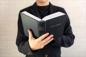 Close-up of Christian man's hands while reading the Bible outside.Sunday readings, Bible education. spirituality and religion concept. Reading a book.